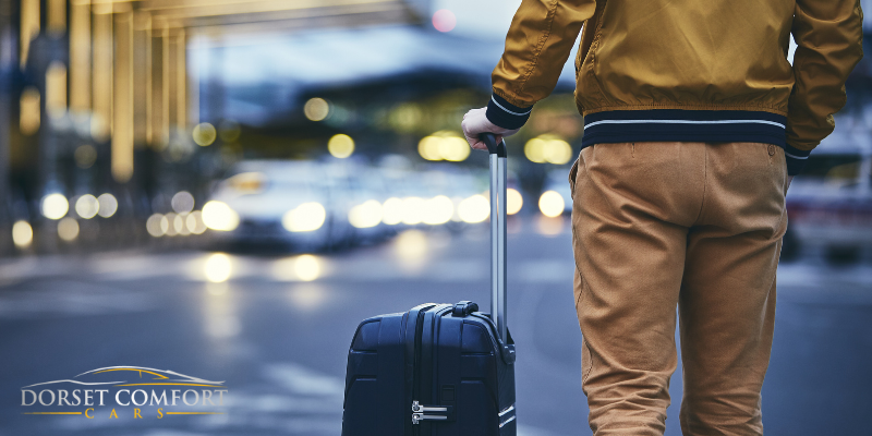 Passenger with a suitcase walking during late hours with blurry car lights in the background.