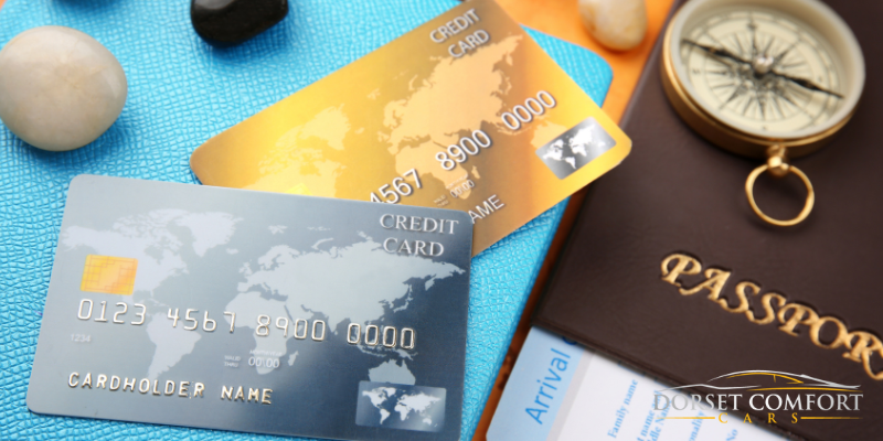 A couple credit cards, a passport and a compass lying on a table.