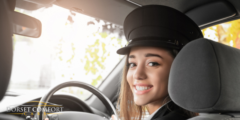 Female Chauffeur sitting behind a steering wheel, smiling whilst looking back.